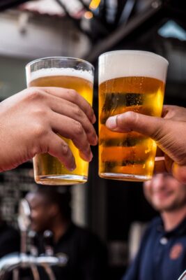 Two people clinking glasses of beer.