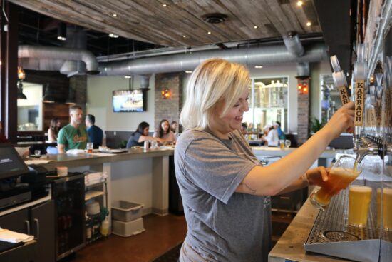Bartender pouring beer from a tap in a bar.