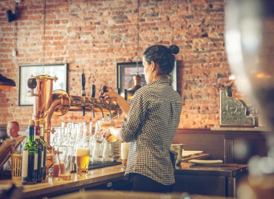 Bartender pouring beer behind a bar counter.