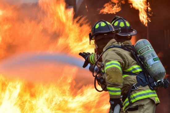 Firefighter spraying water on a large fire.