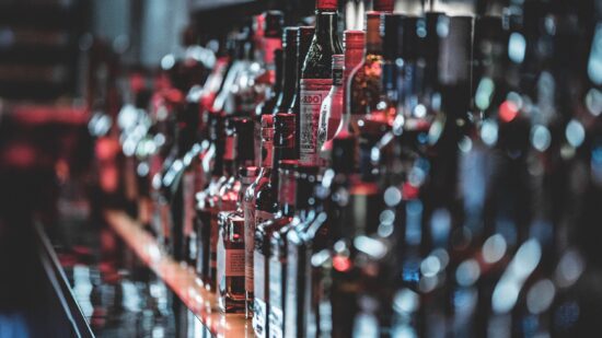 Rows of liquor bottles lined up on a bar.