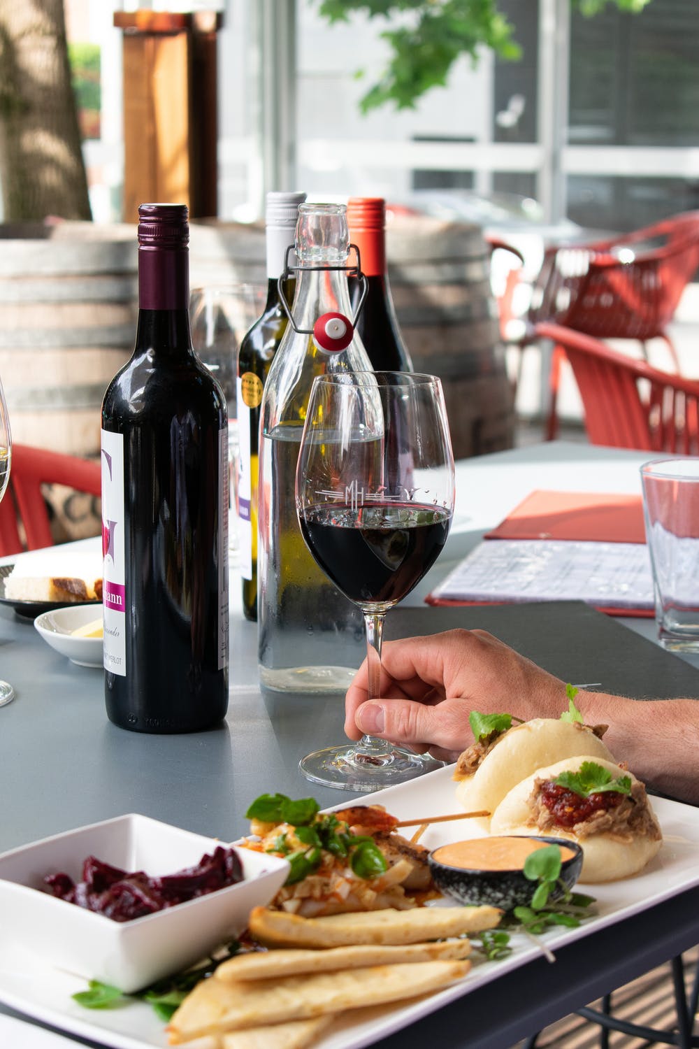 Hand holding a glass of red wine at a restaurant table.