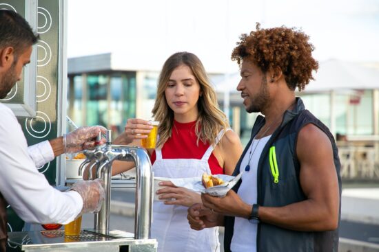 Vendor serving drinks to customers at an outdoor stand.
