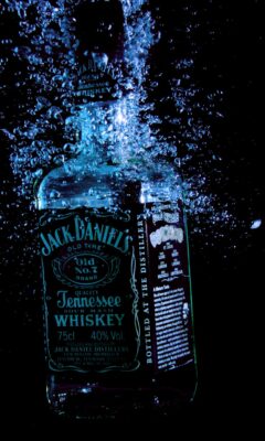Whiskey bottle underwater with splashes.