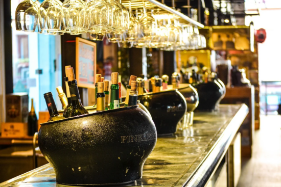 Wine bottles in ice buckets on a bar counter.