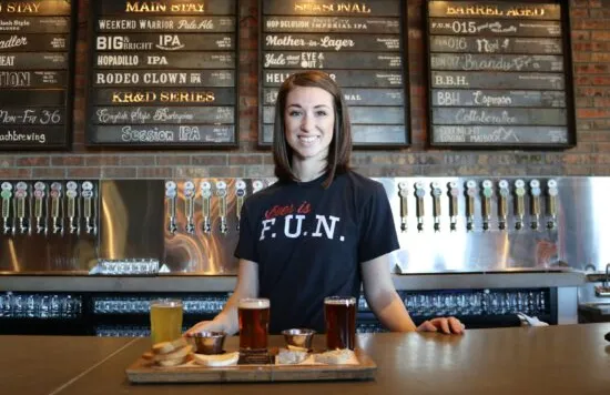 Server standing behind a bar with a beer flight.