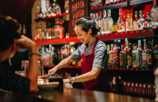 Bartender preparing a drink behind a bar counter.