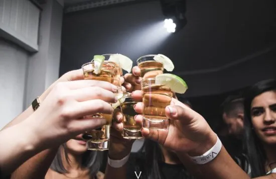 Group of friends clinking shot glasses at a party.