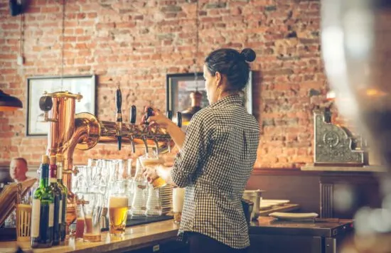 Bartender pouring beer behind a bar counter.