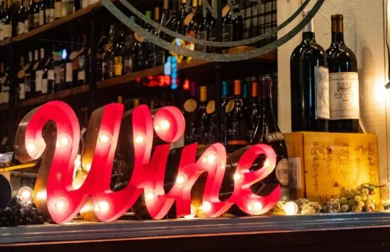 Wine display with illuminated sign and bottles on a shelf.
