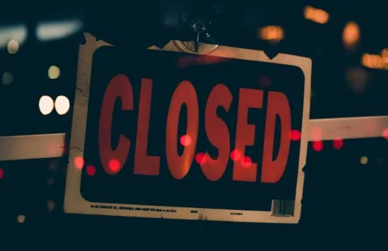 Closed sign hanging on a shop window at night.