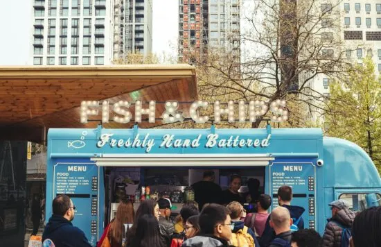 Food truck serving fish and chips with a crowd of people.