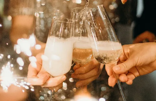 People pouring and holding champagne glasses at a celebration.