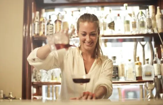 Bartender pouring a drink behind a bar.