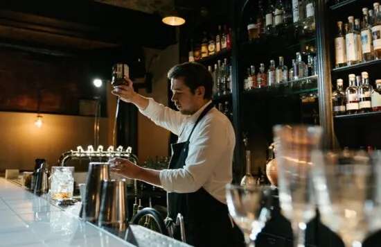 Bartender preparing a drink behind a bar.