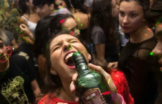 Person playfully posing with a bottle at a party