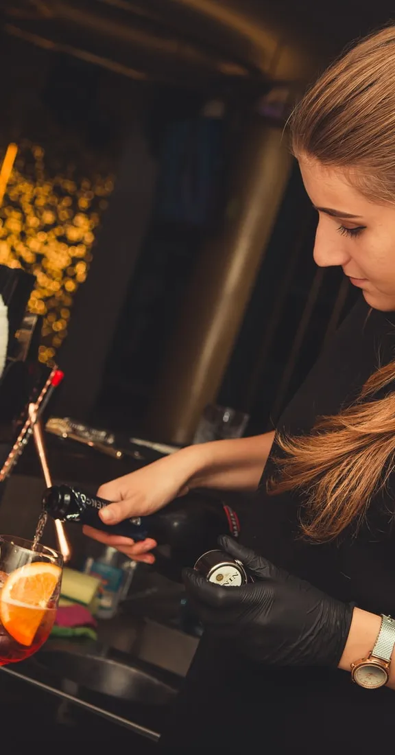 Bartender pouring a drink into two glasses.