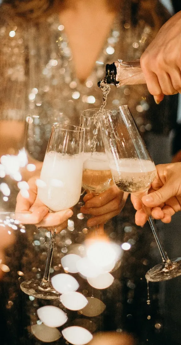 People toasting with champagne glasses while one pours