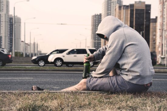 Man beside busy street drinking beer