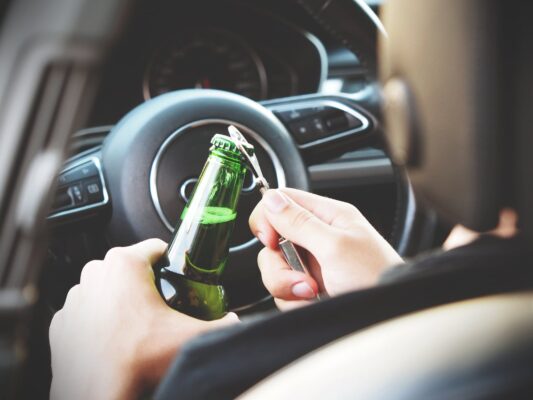 Opening a beer bottle in driver's seat