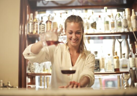 Female bartender smiles while pouring