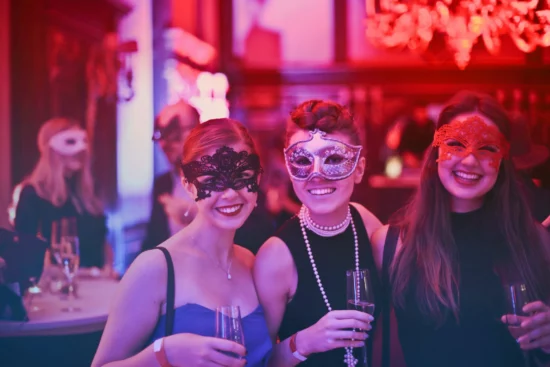 3 women celebrating Halloween at a bar with glasses of wine