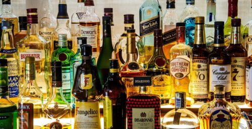 Various brands of alcohol bottles sitting at a bar