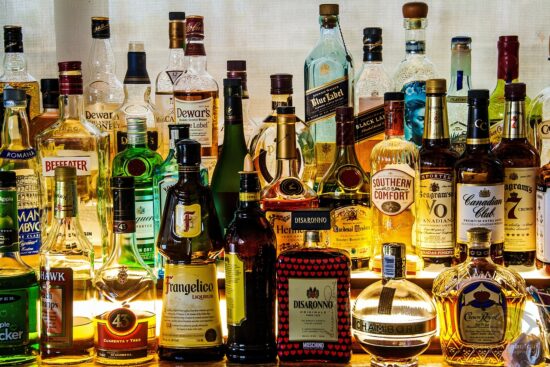 Various brands of alcohol bottles sitting at a bar